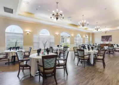 Large dining space with table and chair sets, centerpieces, windows, chandeliers, and hardwood floors